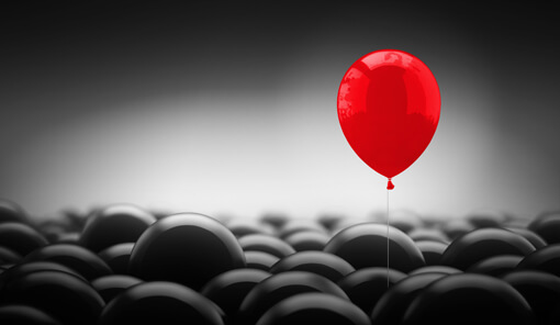 Ballon rouge se démarquant des ballons noirs qui l'entourent